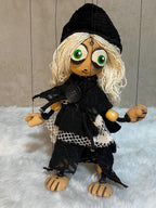 Marionette puppet with blonde hair and black outfit on a textured surface