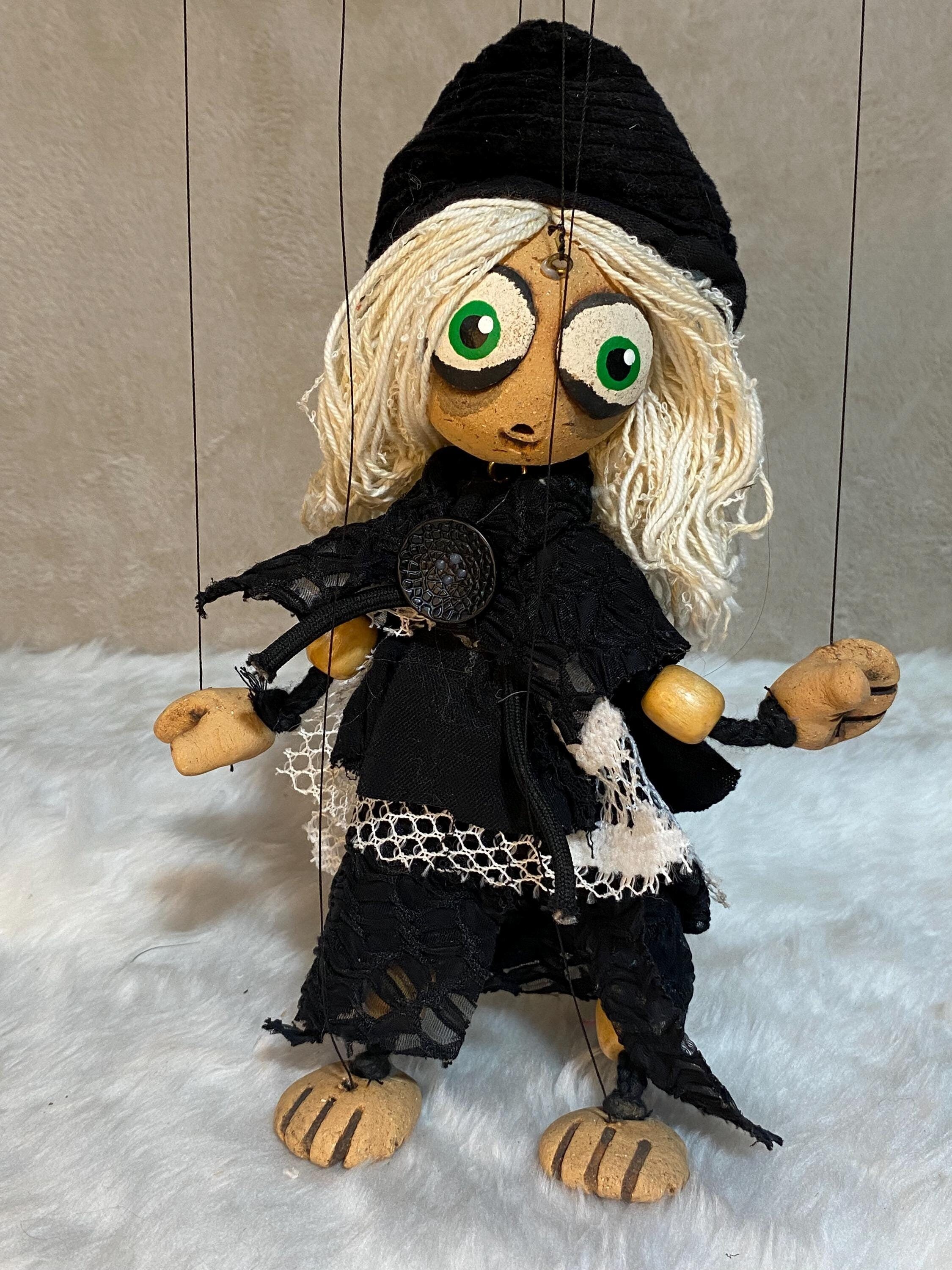 Marionette puppet with blonde hair and black outfit on a textured surface